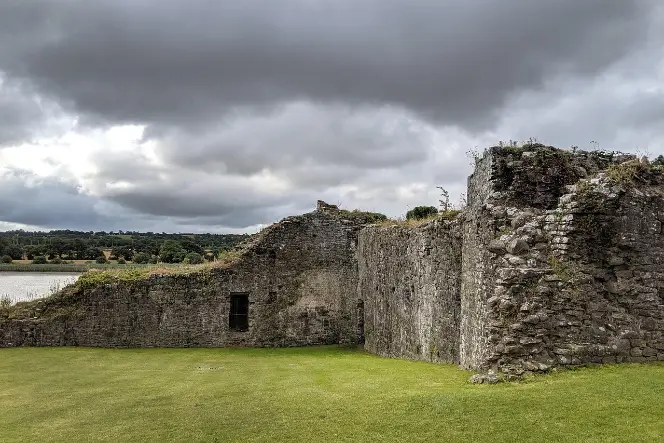 Stone ruins near a peaceful lakeside under a cloudy sky in Ireland, perfect for a calm senior day trip