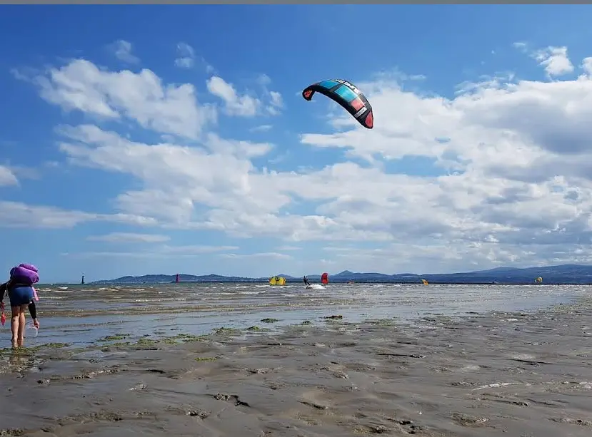 A photo showing people doing paragliding and aerial sports activities on the shore of Dollymount Strand
