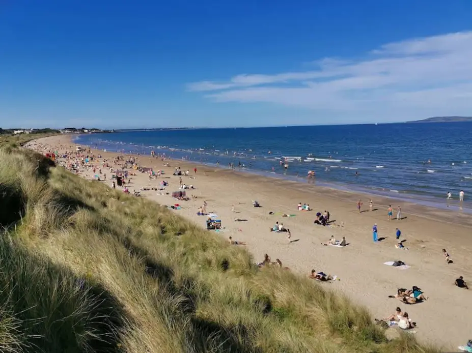 An image shows locals and tourists having beach bliss on the shore of Portmarnock Beach.